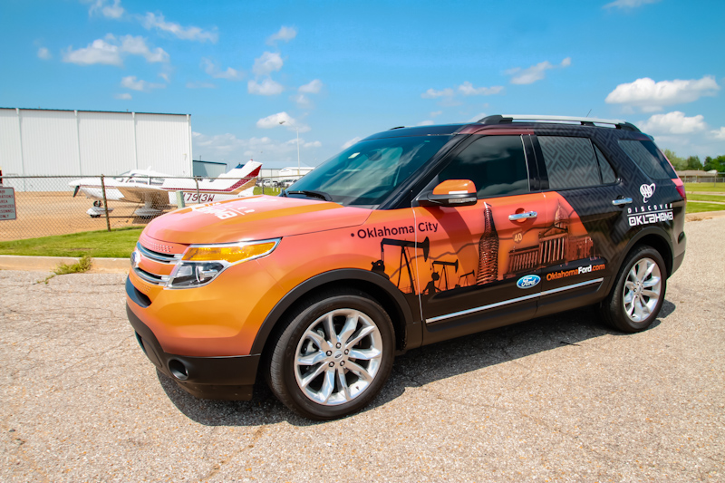 Front drivers view of a Ford Explorer with custom orange and black vehicle wrap
