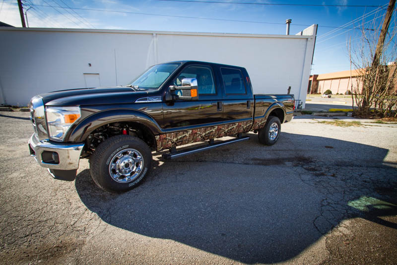 Mossy Oak camouflage wrap on the rocker panels of a Ford F-250. Three quarters view.