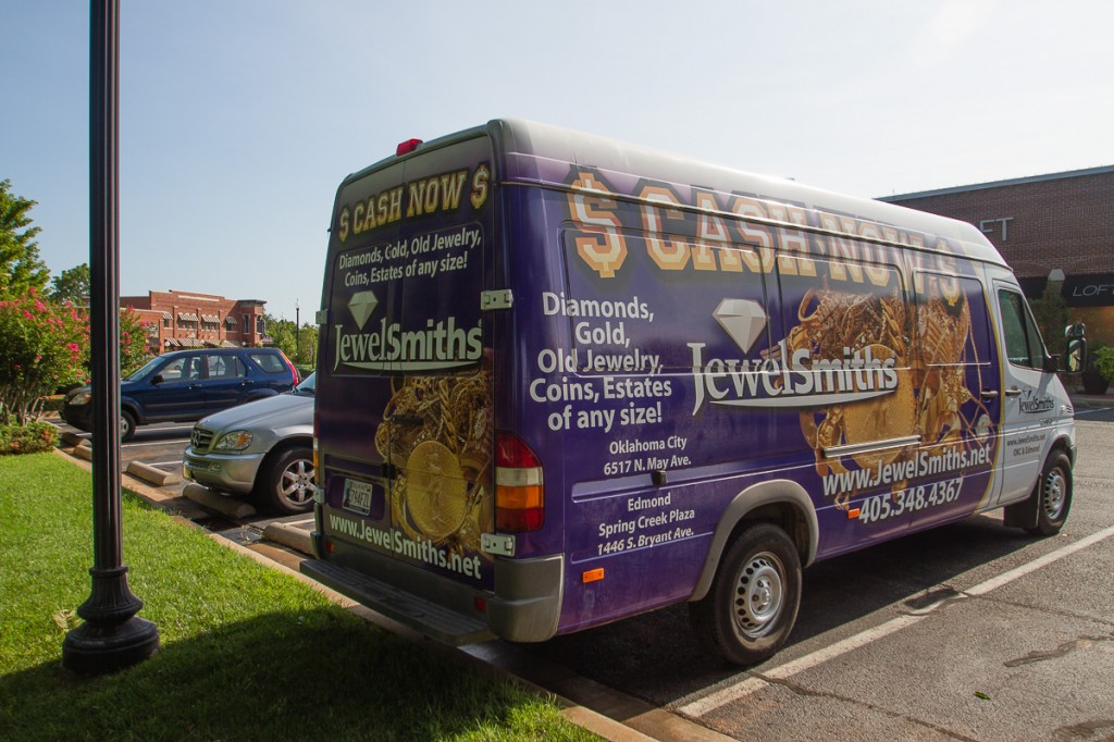 Back quarter view of Sprinter van with gold and purple wrap.